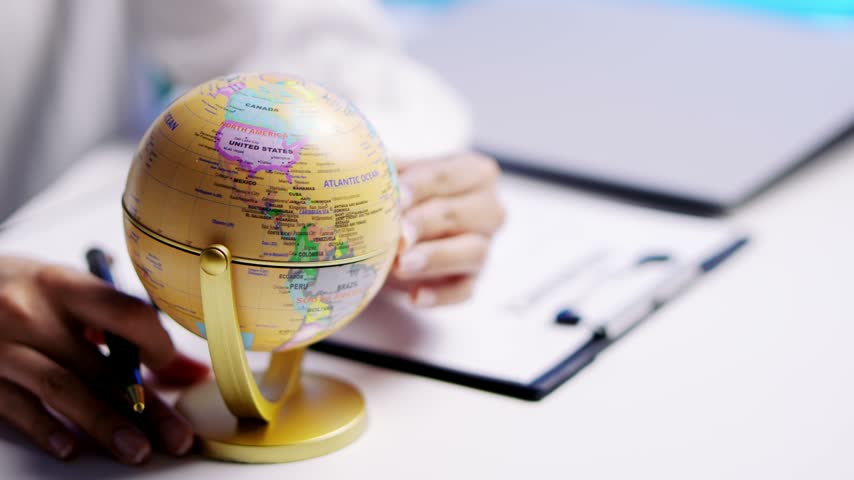 Hand holding small world globe for planning travel destination with curious happy expression, desk professional map exploration journey, global model