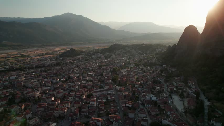 Aerial view of the historic town of Trikala nestled near the dramatic rock formations of Meteora during golden hour, Trikala, Greece.