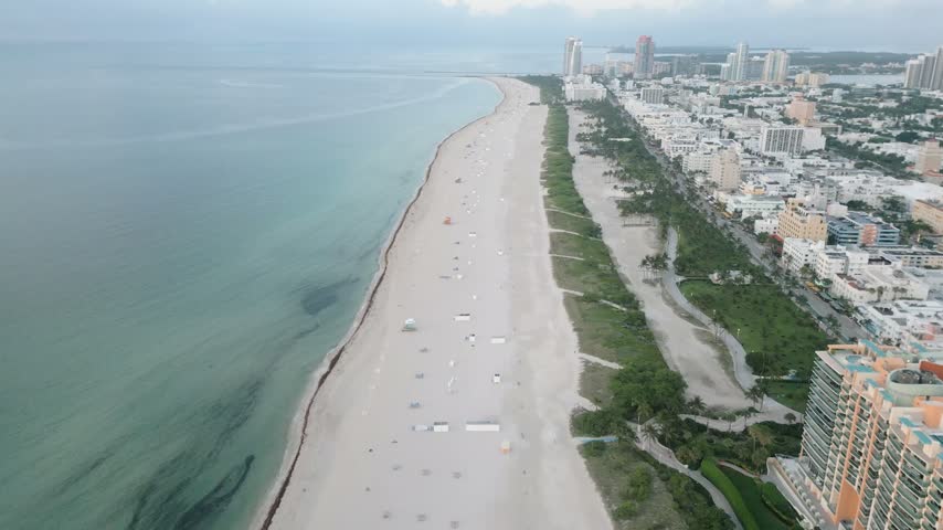 Aerial view of the sandy shoreline and turquoise waters of the Atlantic Ocean along the urban skyline of Miami Beach, Florida, United States.