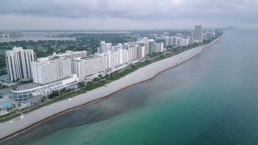 Aerial view of the Miami Beach coastline featuring high-rise hotels and apartments along the sandy beach with turquoise ocean waters in Miami Beach, Florida, United States.