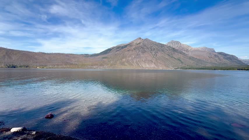 Pan view of mountain range, including Stanton Mountain and Mount Vaught on the banks of Lake McDonald in Glacier National Park