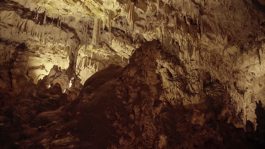 Illuminated underground cavern showcasing natural geological structures with detailed mineral deposits and textured stone walls in a quiet setting