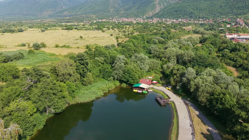 Aerial close-up of a lakeside restaurant and pedal boats at Rila Park in Dupnitsa, Bulgaria.