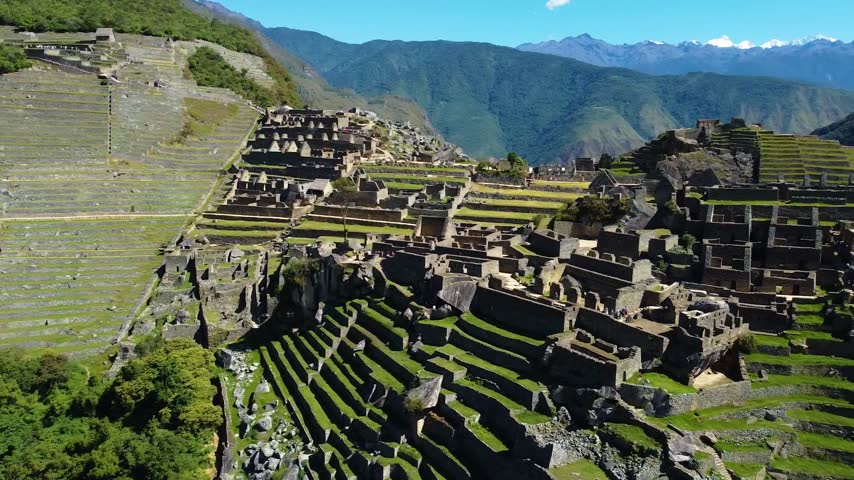 Aerial view of the ancient Inca citadel of Machu Picchu, featuring stone ruins, terraced fields, and surrounding Andean mountains in Urubamba Province, Cusco, Peru.