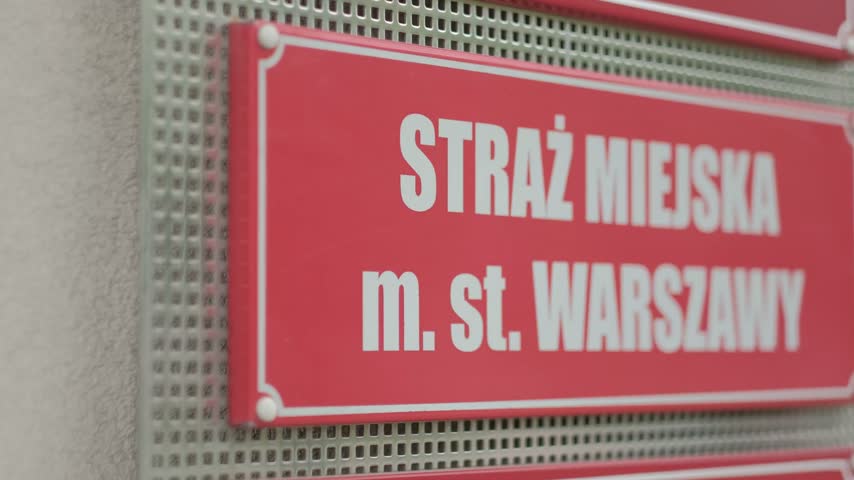 Red municipal police sign for Straż Miejska m. st. Warszawy on a building wall in Warsaw, Poland