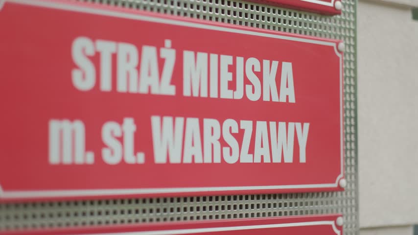Red municipal police sign for Straz Miejska m. st. Warszawy on a building wall in Warsaw, Poland
