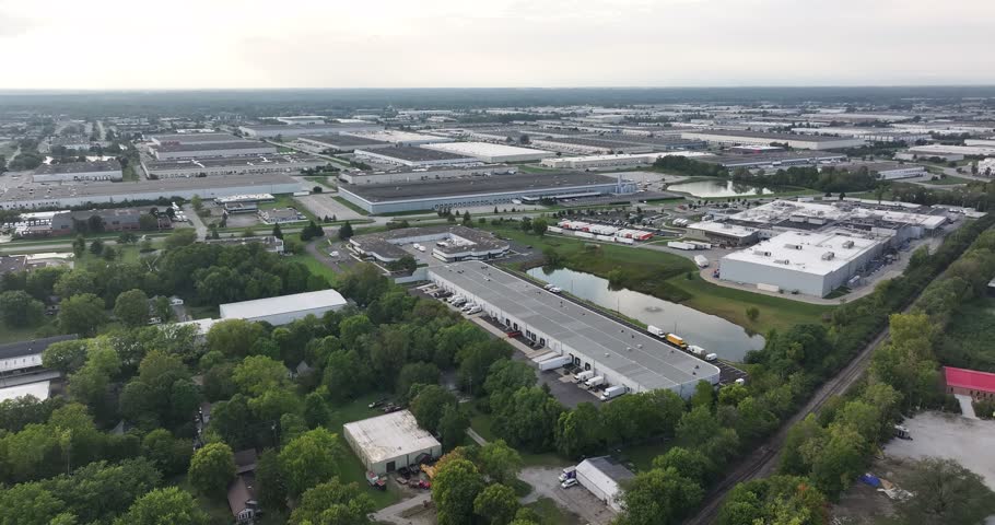 Aerial view of industrial warehouses and logistics facilities with trucks and a pond in Indianapolis, Indiana, United States.