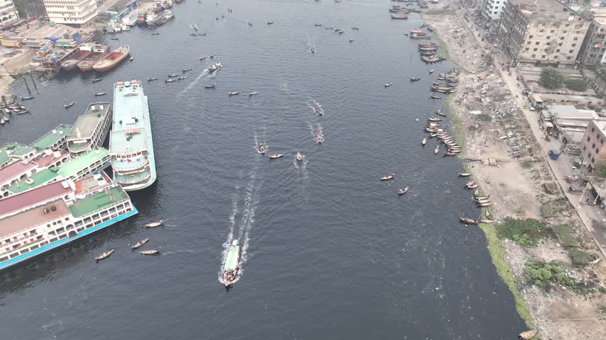Aerial view of Sadarghat river port on the Buriganga River with numerous ferries and small boats navigating the busy waterway in Dhaka, Dhaka Division, Bangladesh.