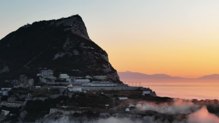 Aerial view of Europa Point and the Rock of Gibraltar at sunset with golden light and mist over the sea in Gibraltar, Gibraltar.