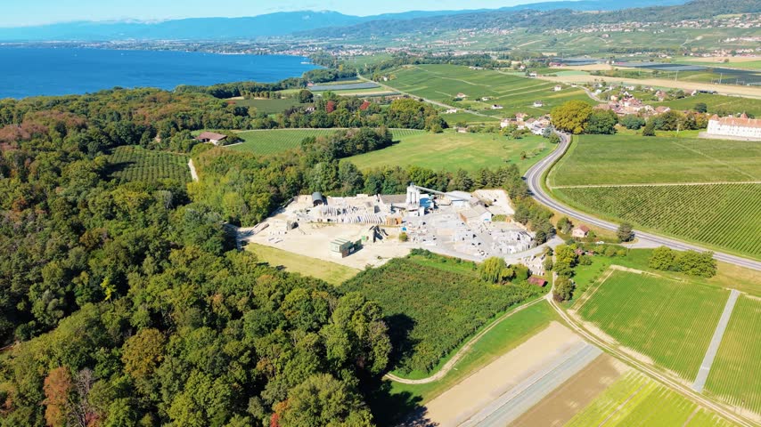 Aerial view of the Cornaz SA - Usine de Chaney industrial facility surrounded by lush green vineyards and forests near Lake Geneva in Allaman, Vaud, Switzerland.