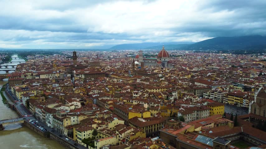 Aerial view of the historic Florence cityscape featuring the iconic Duomo cathedral surrounded by terracotta rooftops under a cloudy sky in Florence, Tuscany, Italy.