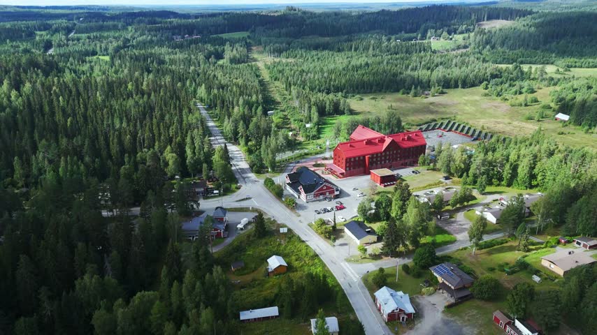Aerial view of the red hotel complex surrounded by dense forests and roads in Lieksa, North Karelia, Finland.