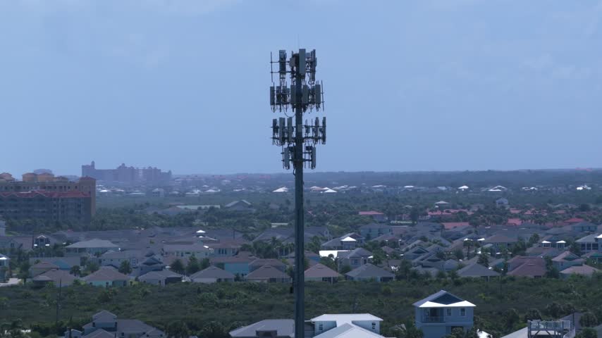 Aerial view of a tall cell tower rising above the residential rooftops and lush vegetation of Summer Haven in St. Johns County, Florida, United States.