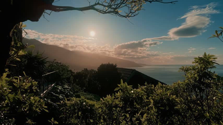 Serene sunrise over mountainous coastline with lush vegetation and ocean view