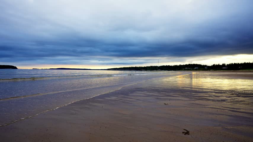 New River Beach Provincial Park sandy tidal shoreline under dramatic overcast twilight skies along the Bay of Fundy, New Brunswick.