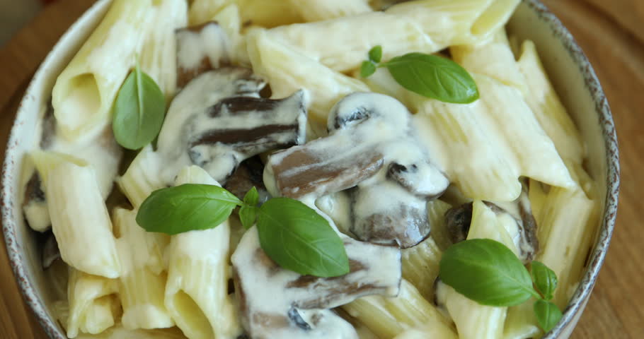 Tasty pasta with mushrooms, cheese and basil on table, closeup