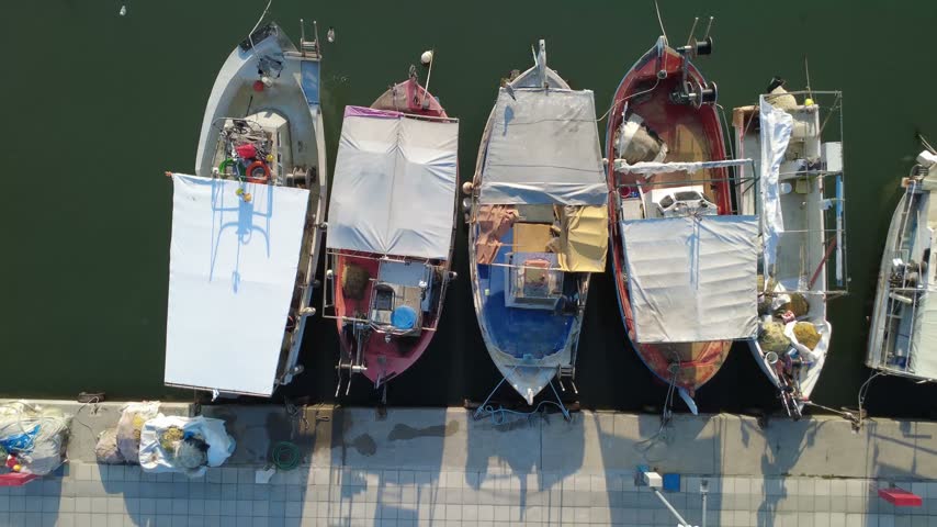 Aerial view of fishing boats moored at the port of Paralia, with white covers and calm water in Paralia, Katerini, Greece.