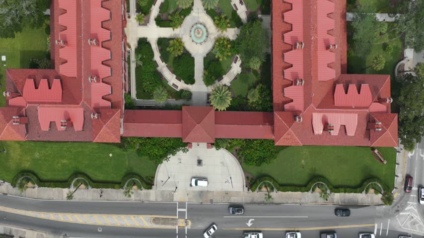 Aerial view of the historic Flagler College campus with its distinctive red roofs, lush green courtyards, and central fountain in St. Augustine, Florida, United States.