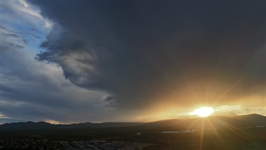 Aerial view of massive dark storm clouds expanding over the landscape during a vibrant sunset in White Rock, NM, United States.
