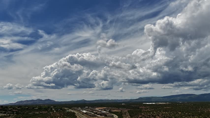 Aerial view of dramatic clouds shifting over a southwestern town and mountain range in White Rock, NM, United States.