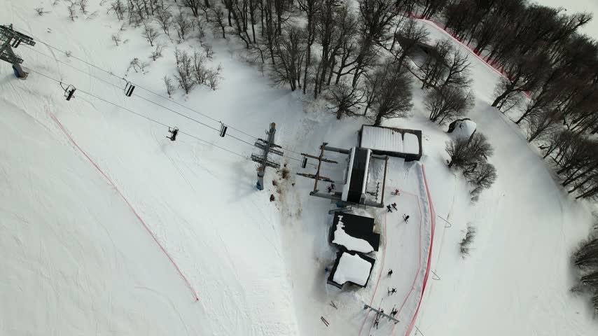 Aerial view of the Cerro Catedral ski lift station surrounded by snow-covered slopes and trees in Bariloche Department, Rio Negro Province, Argentina.