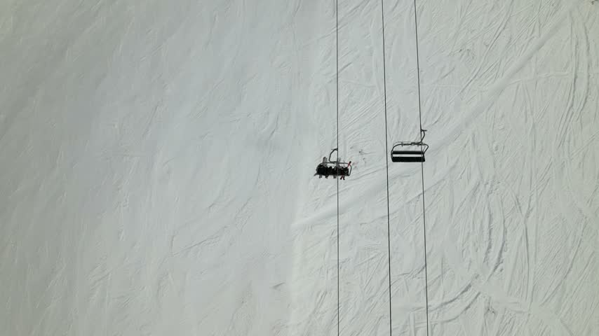 Aerial view of Cerro Catedral ski lift with chairs moving over snow-covered slopes in Bariloche Department, Rio Negro Province, Argentina.