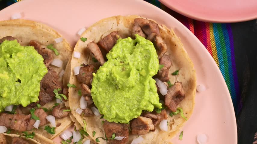Mexican Street Tacos de asada with chopped meat, onions and guacamole sauce