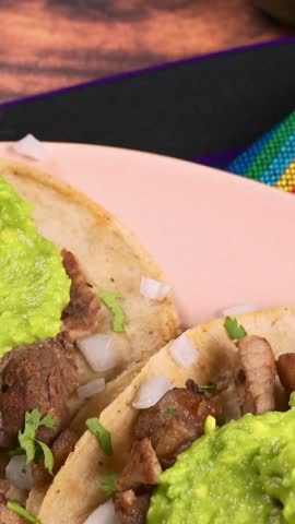 Traditional Mexican carne asada tacos with green guacamole salsa and chopped onions served on warm tortillas