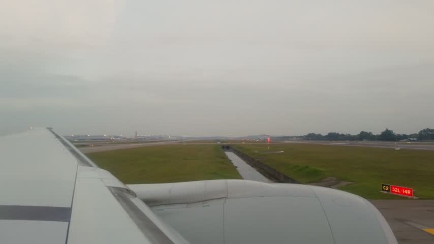 A 4K 5x speed time-lapse POV shot from a passenger window shows an aircraft taking off from Kuala Lumpur International Airport and ascending into the cloudy sky.