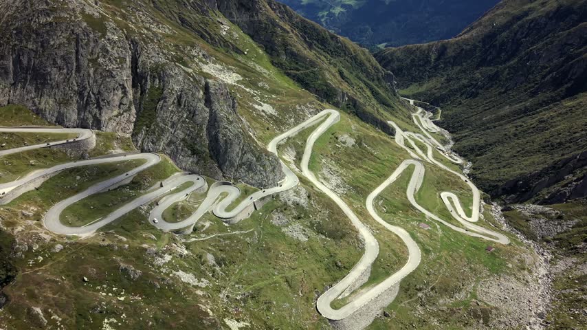 Aerial dolly forward tilt down over Gotthard Pass winding alpine road.