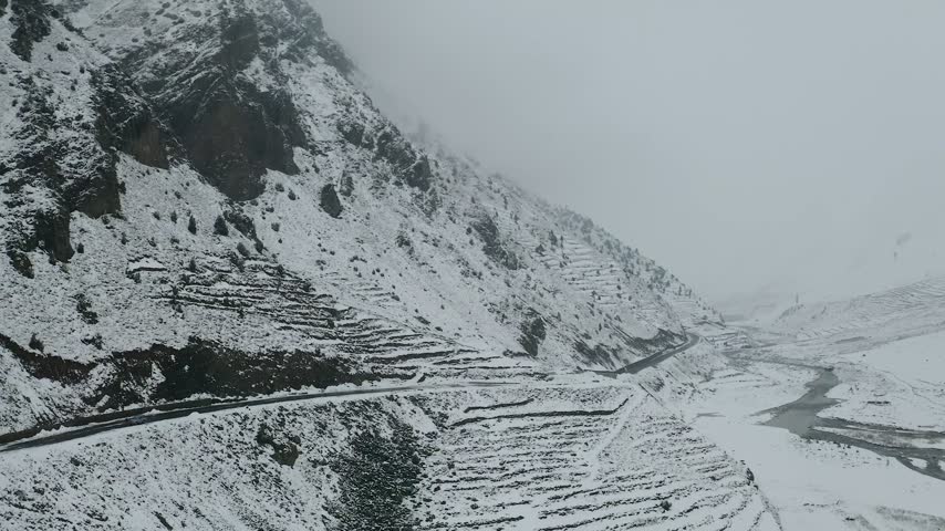 Aerial view of the snow-covered Naran Kaghan mountain road winding through the rugged landscape of KPK, Pakistan.