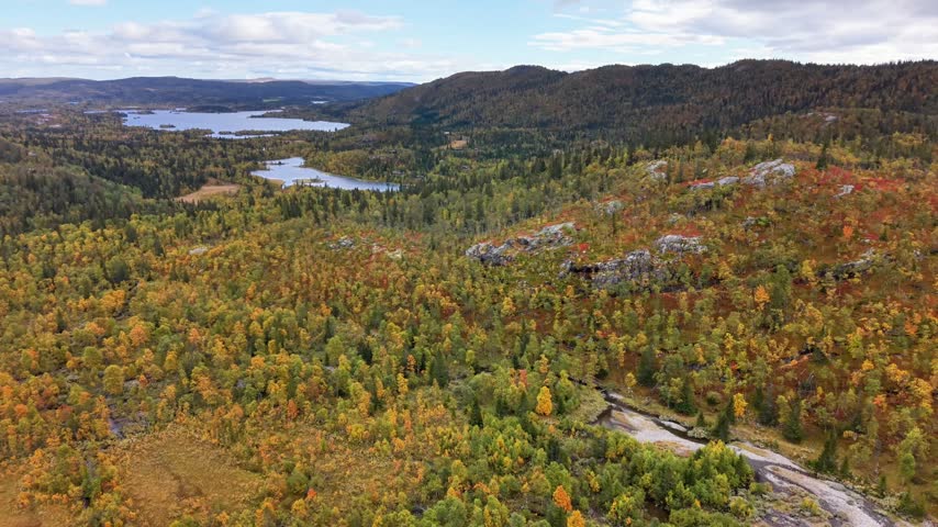 Aerial view of autumn landscape with colorful trees, rocky outcrops, and winding streams in the mountains of Hemsdal Municipality, Buskerud, Norway.
