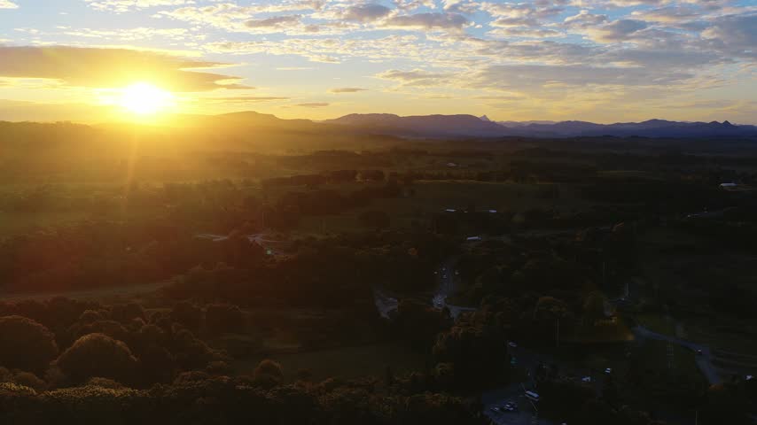Aerial view of sunset over rural landscape with macadamia trees and farmland in Byron Bay, New South Wales, Australia.