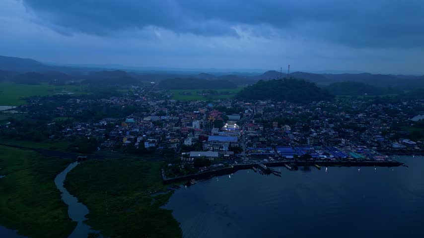 Aerial view of Buhi town and Lake Buhi during blue hour in Camarines Sur, Philippines. The town, lakeshore, surrounding landscape and Mount Asog, also known as Mount Iriga, are visible in the backgrou