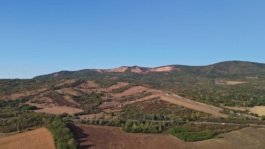 Naszály Hill quarry near Vác in Pest County, Hungary, with Triassic limestone extraction, forested hillsides, rural fields and roadway infrastructure in an aerial view.