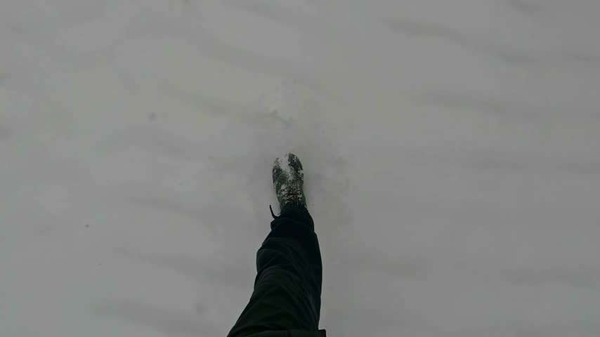 POV of hiking in pristine deep snow, capturing an immersive winter adventure through a cold, cloudy landscape.