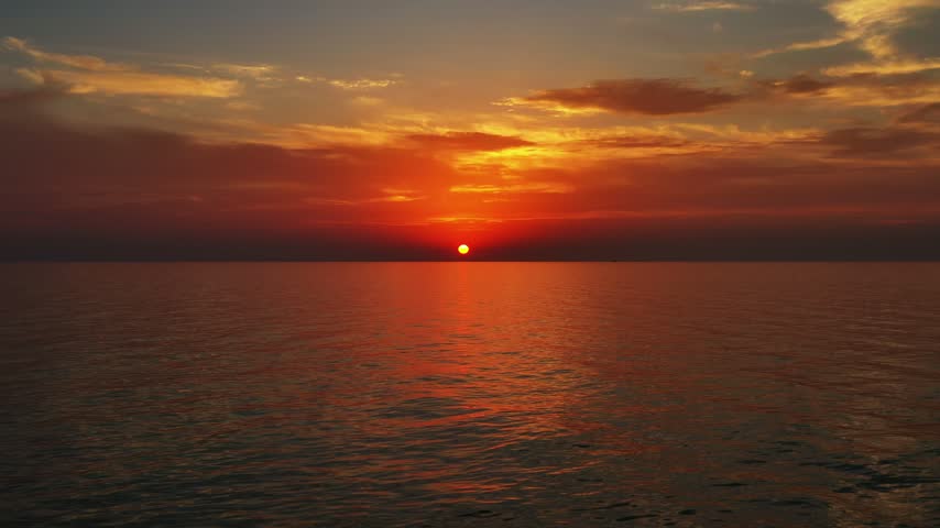 Aerial view of sunset over the calm sea with vibrant orange and red sky reflecting on the water surface Montenegro.