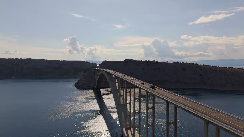 Aerial view of Krk Bridge spanning the Adriatic Sea with cars driving across in Smrika, Primorje-Gorski Kotar, Croatia.