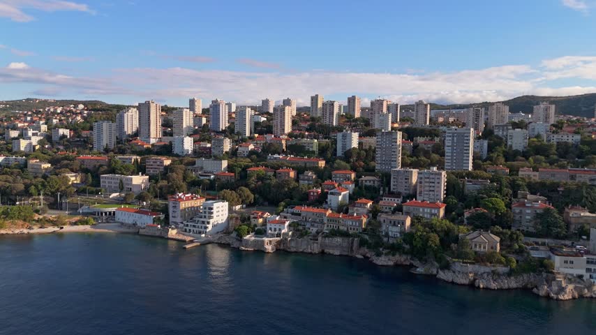 Aerial view of the coastal city of Rijeka featuring residential apartment blocks, lush greenery, and the Adriatic Sea coastline in Rijeka, Primorje-Gorski Kotar, Croatia.