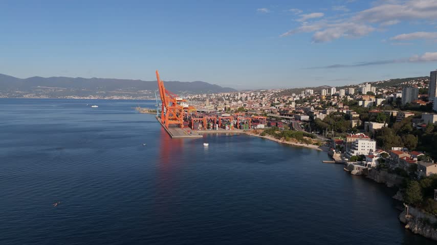Aerial view of the industrial port of Rijeka with large cranes and shipping containers along the coastline in Rijeka, Primorje-Gorski Kotar, Croatia.