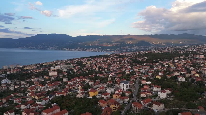 Aerial view of the coastal city of Rijeka with red-tiled rooftops, lush greenery, and the Adriatic Sea in the background, Rijeka, Primorje-Gorski Kotar, Croatia.