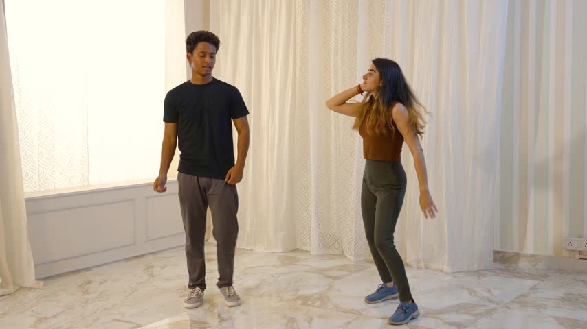 An Indian couple practicing dance moves together indoors