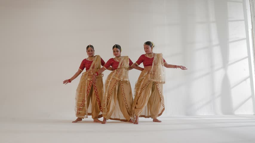 Three Indian women performing a traditional dance in a studio environment