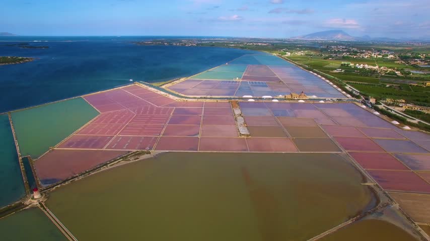 Aerial view of the colorful salt evaporation ponds and historic windmill at the Trapani Salt Pans in Sicily, Italy.
