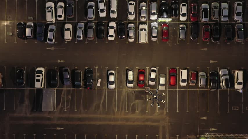 Aerial view of a parking lot filled with parked cars at night in Russia.