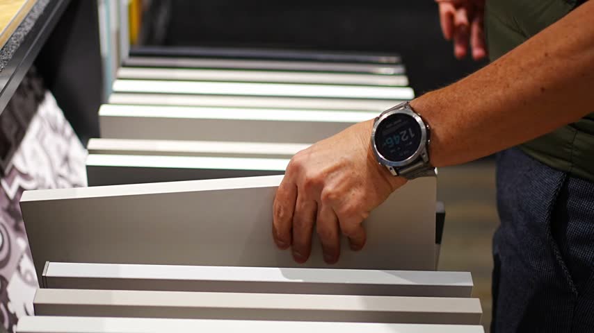Man browses cabinet door samples in furniture showroom. Choosing colors and finishes for kitchen renovation with selective focus and soft background.