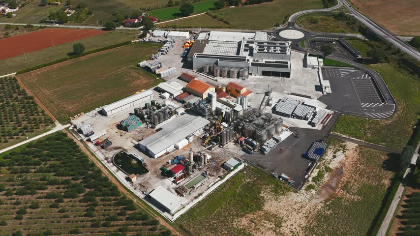 Aerial view of industrial facility with storage tanks and warehouses surrounded by fields in Spoleto, Umbria, Italy.