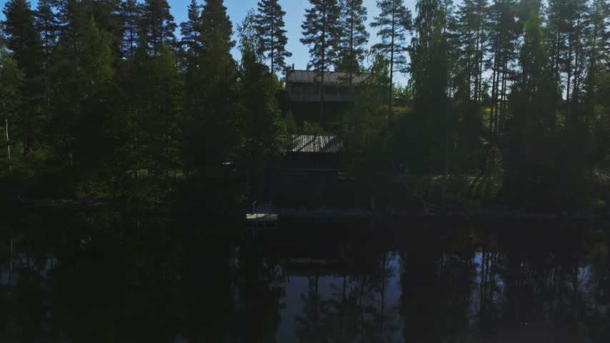 Aerial view of a wooden house nestled in the dense forest by a calm lake in Koli National Park, Lieksa, North Karelia, Finland.