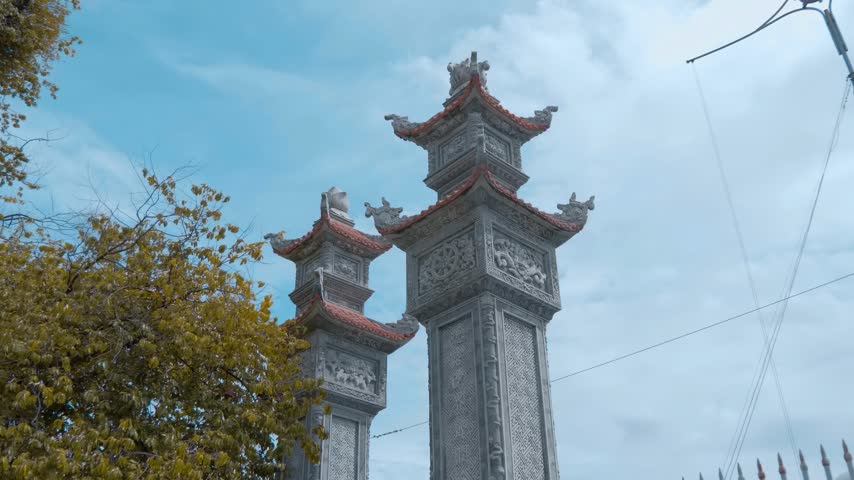 Intricate stone architecture of the Hai Duc Buddhist Institute located on Trai Thuy Hill in Nha Trang, Vietnam featuring memorial stone pillars with detailed carvings and small multi-tiered tiled roofs. Shot in motion