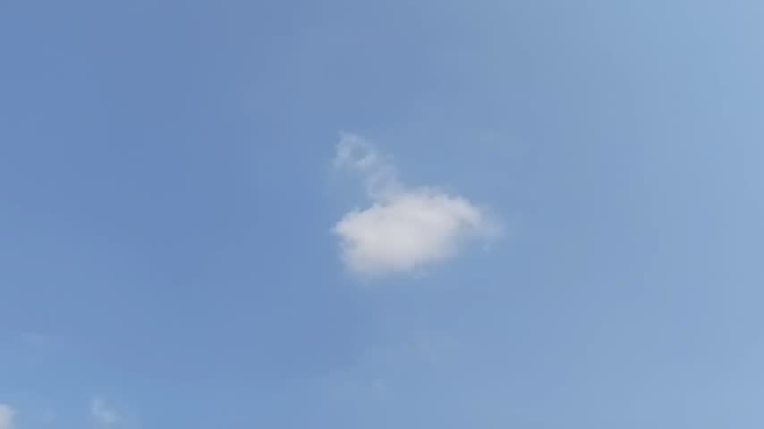 A single fluffy white cloud floating gently in the clear blue sky on a bright sunny day
